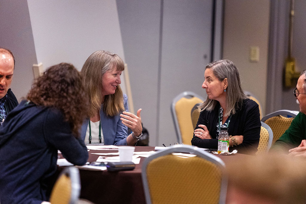 Two women seated at a table in discussion at the 2025 NetVUE Conference.