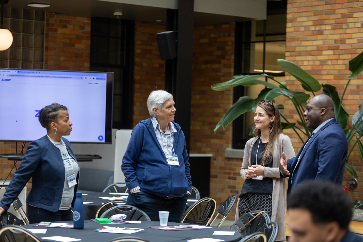 A group of four individual standing together prior to the start of the 2024 NetVUE regional gathering at Calvin University.