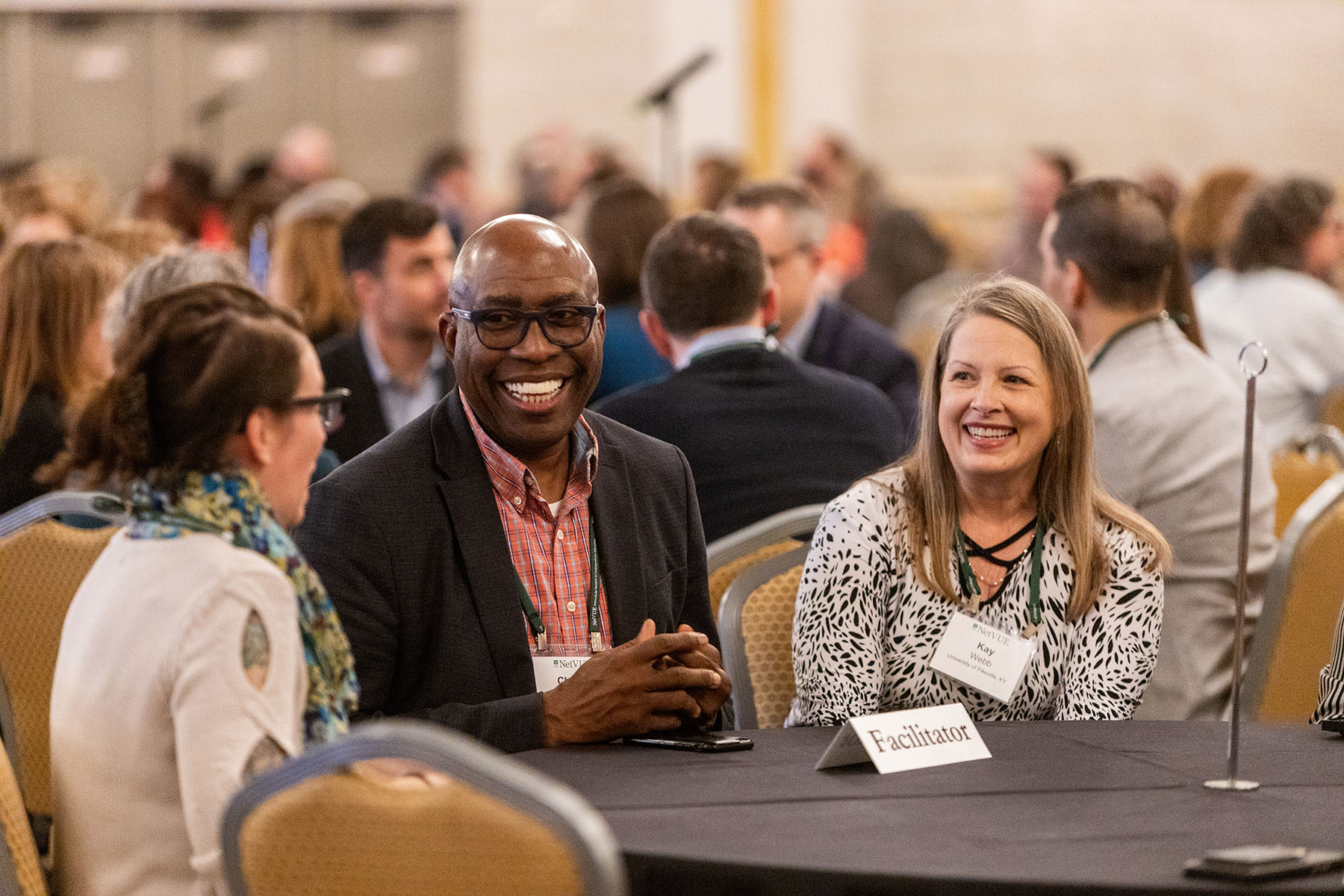 Several people laughing together, seated at a round table.