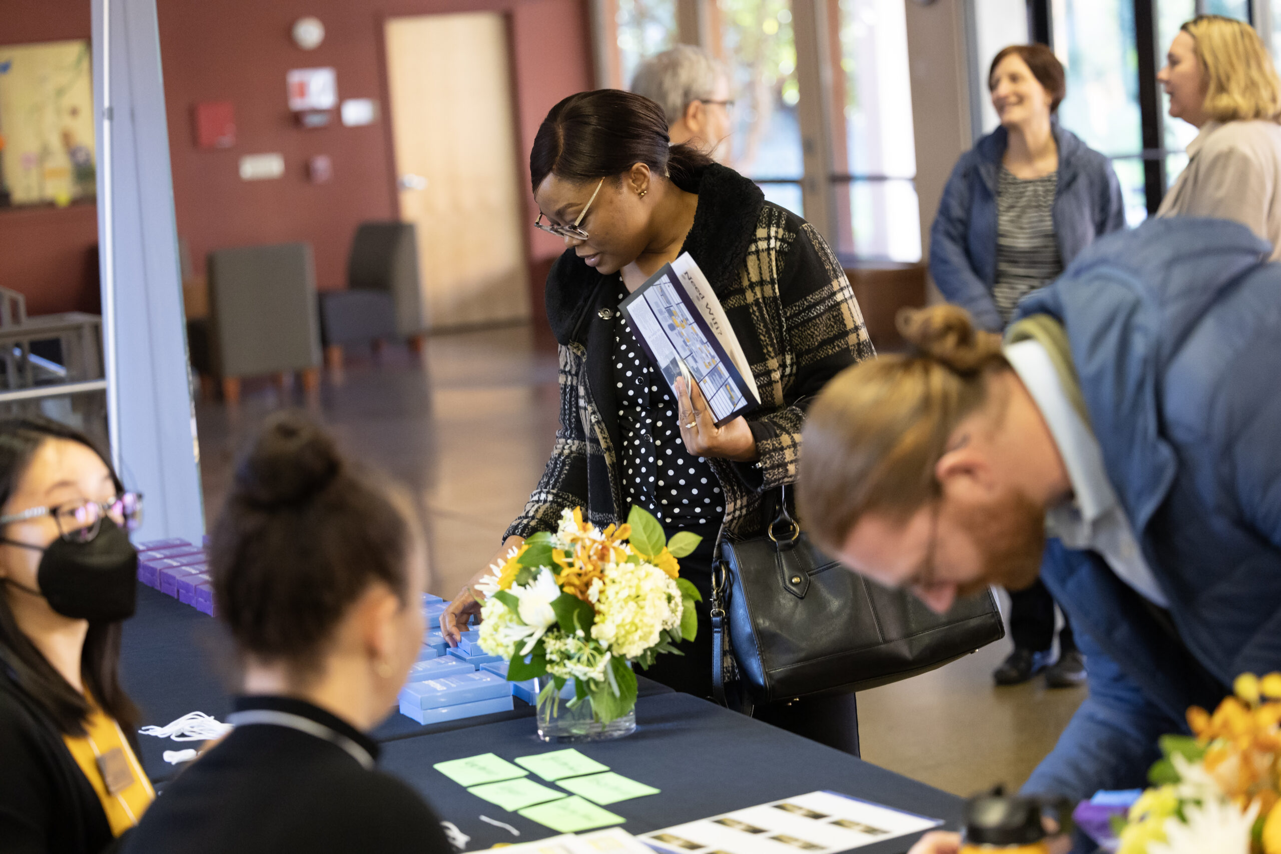 A woman peruses the registration table where decks of NetVUE Conversation Cards are on display at the 2025 NetVUE regional gathering at Pacific Lutheran University.