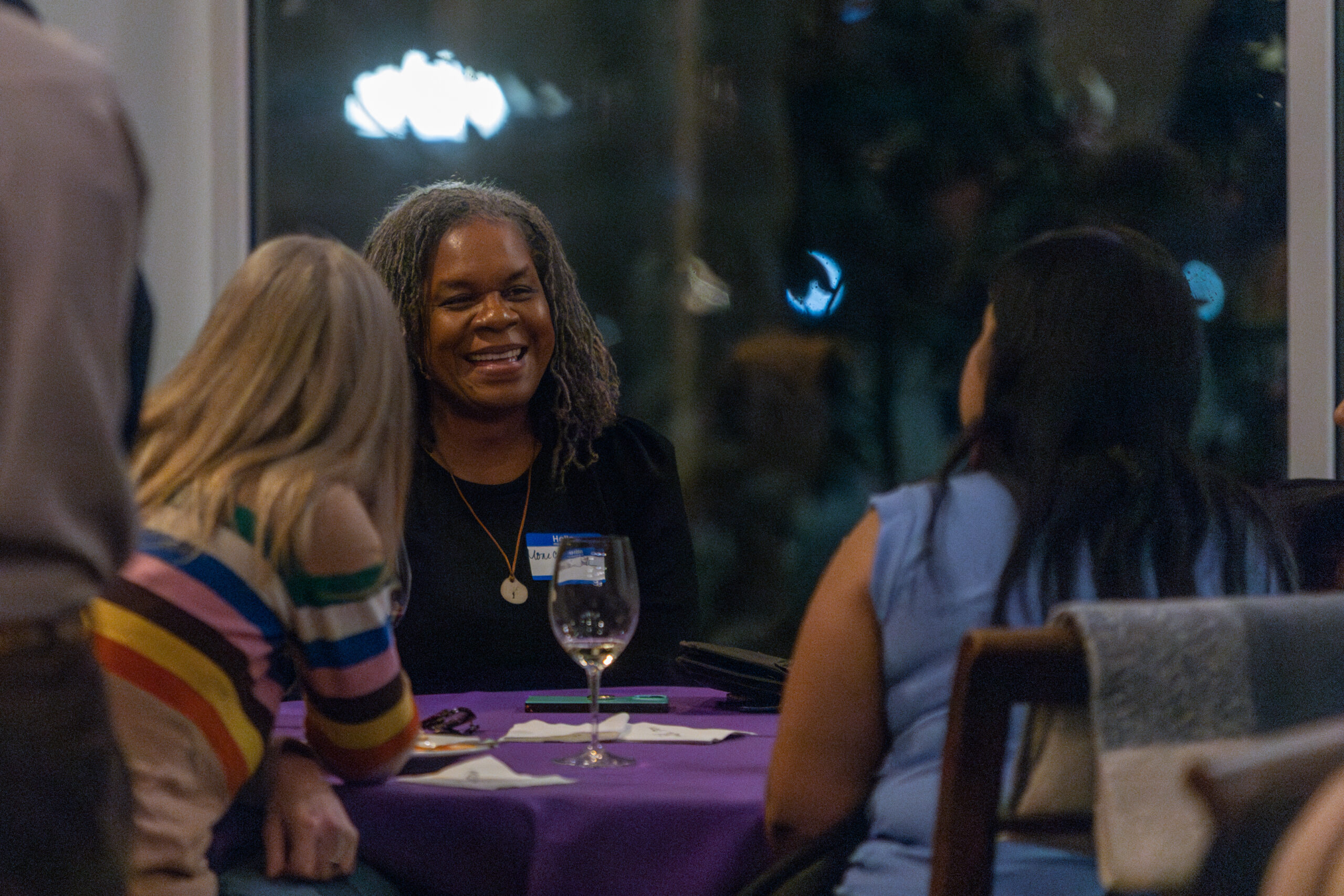 A woman seated with her colleagues at a dining table.