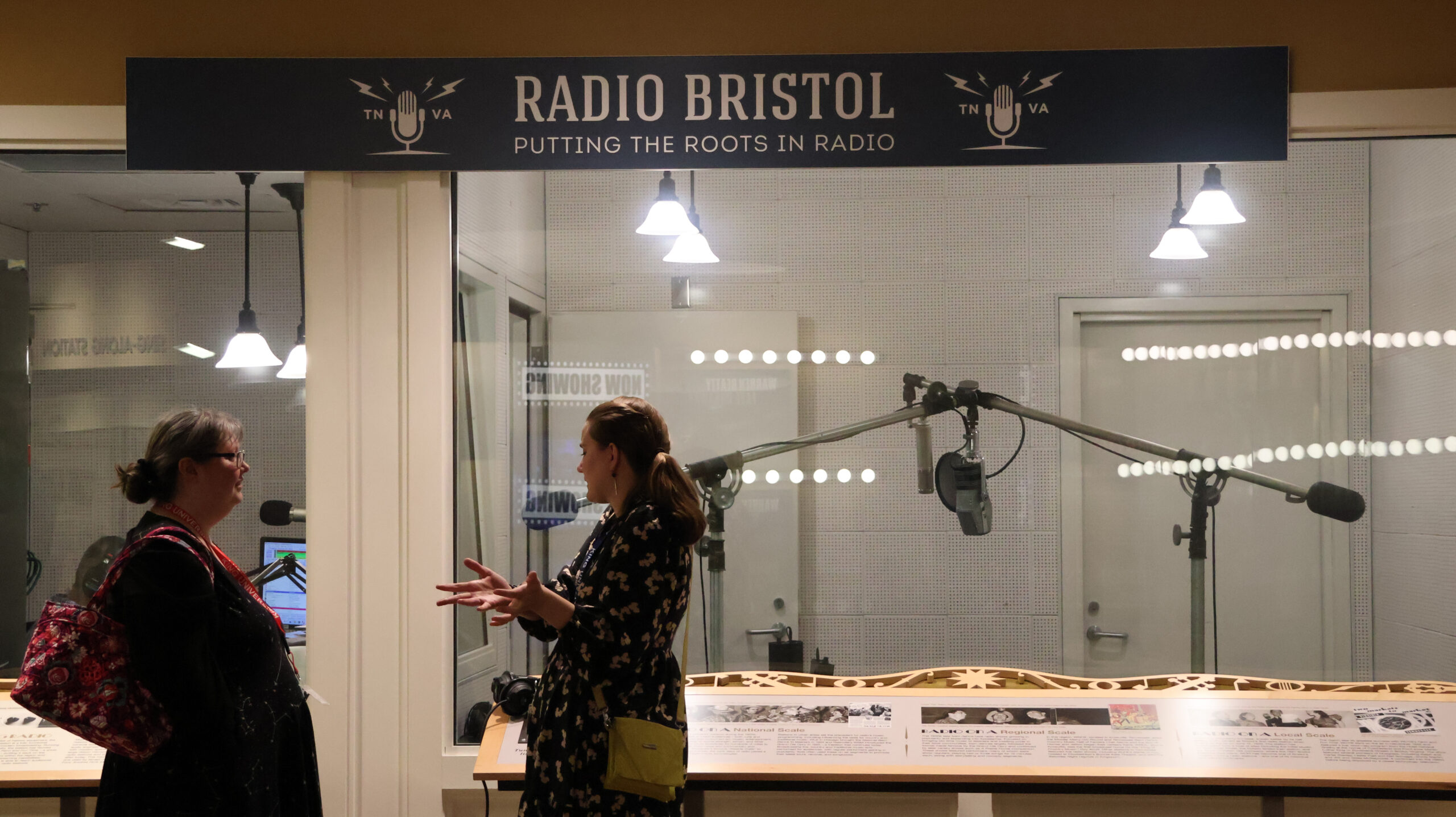 Two participants of the 2024 NetVUE regional gathering hosted by King University speak in front of a radio booth at the Birthplace of Country Music Museum in Bristol, VA.