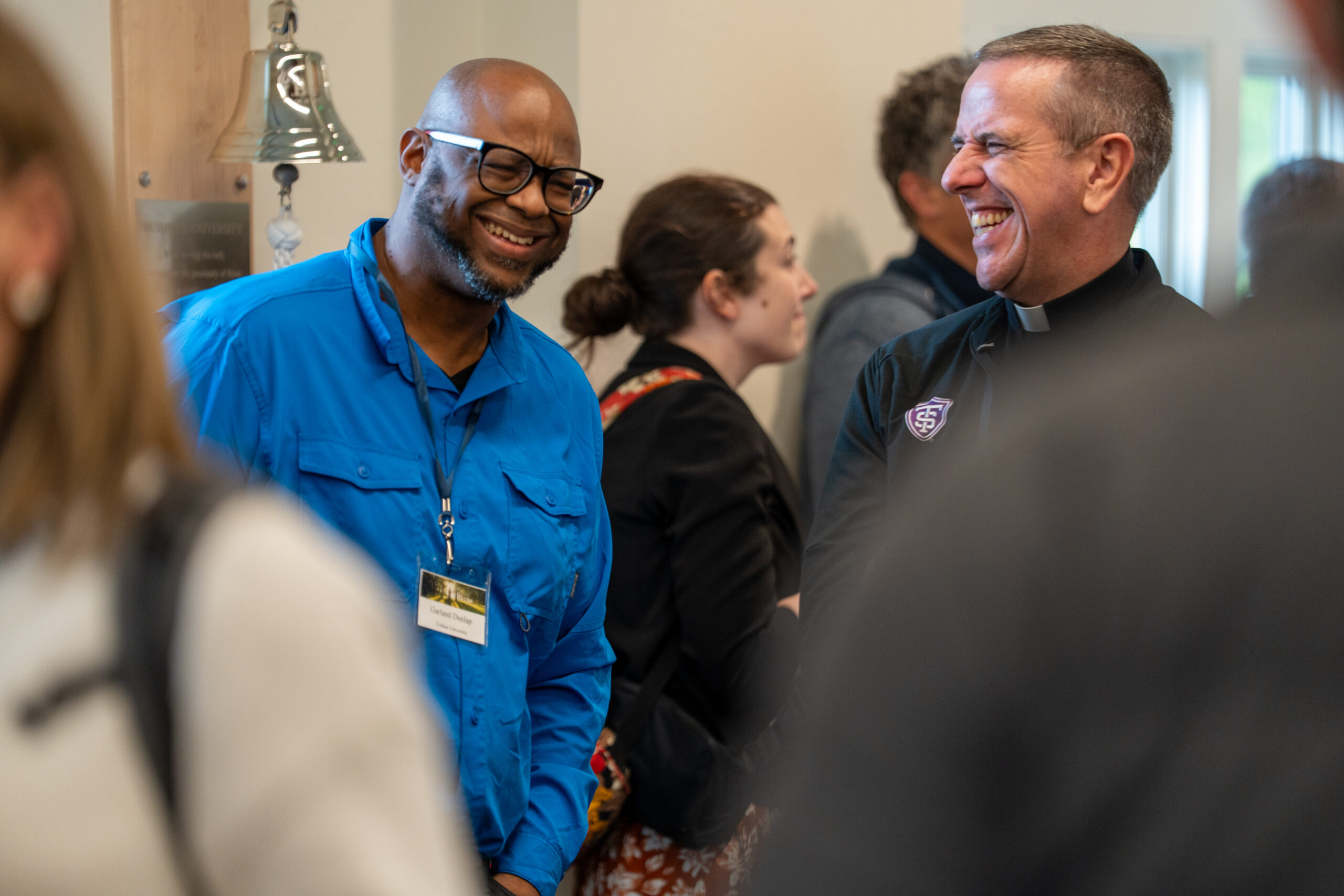 Two men laughing together in a crowd.